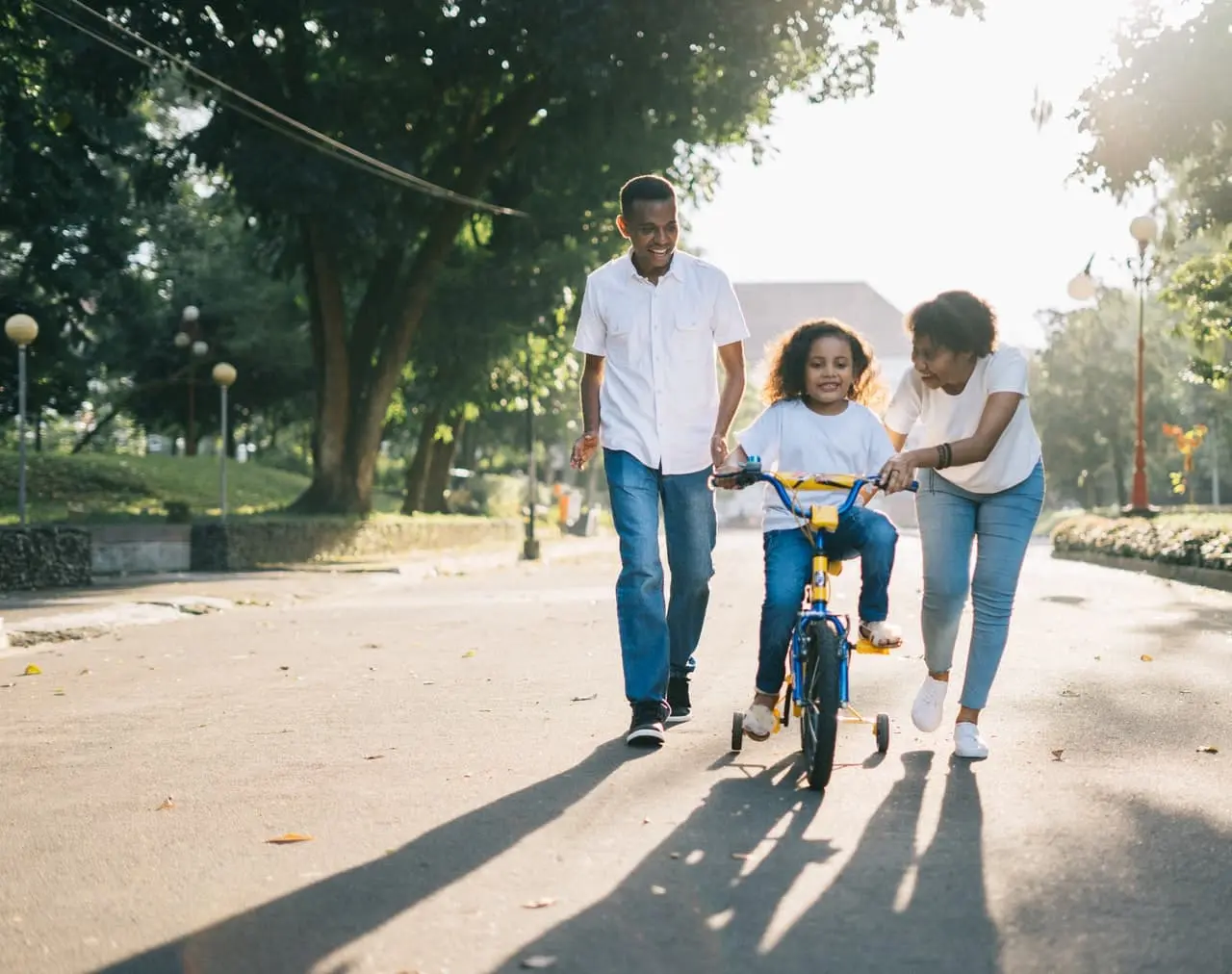A family teaching their daughter to ride a bike